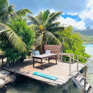 a wooden dock with a table and chairs on the water at Teraupoo Lodge Maison in Afareaitu