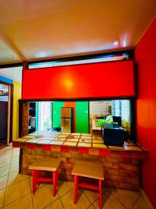 eine Bar mit zwei Bänken und einer roten und grünen Wand in der Unterkunft Teraupoo Lodge Maison in Afareaitu