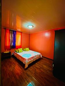 Teraupoo Lodge Maison في Afareaitu: غرفة نوم بجدران برتقالية وسرير بمخدات صفراء