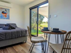 a room with a table and a bed and a table and chairs at Trinity Islands Holiday Park - Cabin Accommodation in Burrum Heads