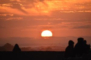 ピチレムにあるSURFHOUSE Pichilemuの夕日を眺めながら海岸に座る人々