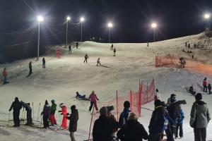 un gruppo di persone su una pista sciistica di notte di Šumski raj a Desmerice