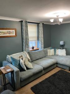 a living room with a gray couch and a window at Ivy House, three bed cottage, parking garden in Skipsea