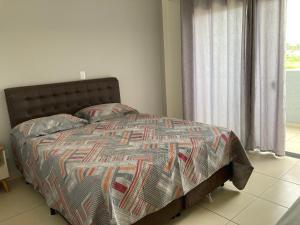 uma cama com um edredão e almofadas num quarto em Pousada Barra Coast em Barra Velha