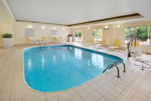 a pool in a hotel room with chairs and tables at Fairfield Inn & Suites Indianapolis Airport in Indianapolis