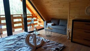 una camera con un letto e un divano in una cabina di Las Lorien - wynajem domków letniskowych 2.0 a Roczyny