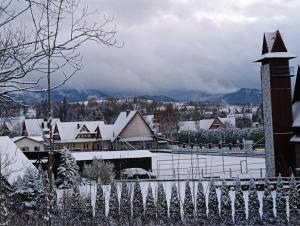 a town covered in snow with a fence at Apartamenty Baciarskie in Poronin