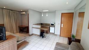 a living room with a couch and a kitchen at Flat completo - Sun Square in Goiânia