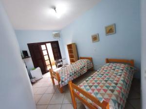 a bedroom with two beds and a door to a room at Morro do Forte in Guarujá