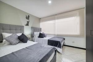 1 dormitorio con 2 camas y ventana en Amplios departamentos en Envigado en Envigado