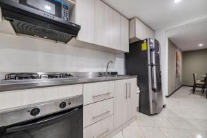 a kitchen with a stove and a refrigerator at Amplios departamentos en Envigado in Envigado