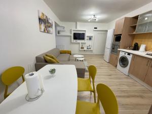 a living room and kitchen with a white table and yellow chairs at Yellow Apartment in Floreşti