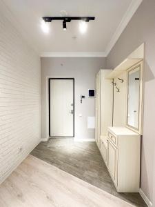 Cette chambre blanche dispose d'une porte et d'un miroir. dans l'établissement 2-комнатные апартаменты в жилом комплексе Zaman, à Atyraū