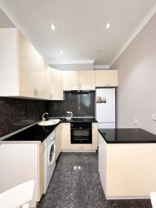 une cuisine avec des armoires blanches et des comptoirs noirs dans l'établissement 2-комнатные апартаменты в жилом комплексе Zaman, à Atyraū