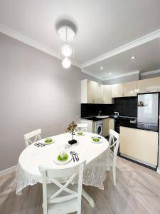 - une table blanche avec des chaises blanches dans la cuisine dans l'établissement 2-комнатные апартаменты в жилом комплексе Zaman, à Atyraū