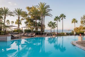 a swimming pool with palm trees and the ocean at Marriott's Playa Andaluza in Estepona