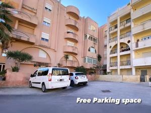 two white vans parked in a parking lot in front of a building at La Salinella in Marsala