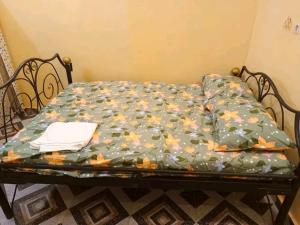 a bed with a green comforter with flowers on it at Villa meublée de saaba in Dassasgo