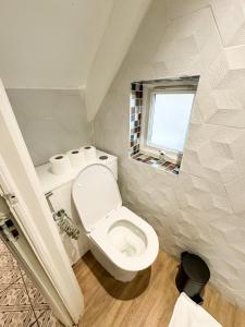 La salle de bains est pourvue de toilettes blanches et d'une fenêtre. dans l'établissement Beahive house, à Redbridge