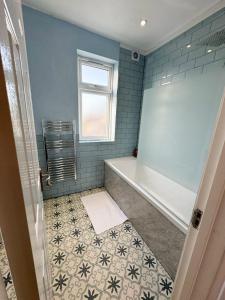 a bathroom with a tub and a tile floor at Beahive house in Redbridge