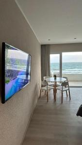 een woonkamer met een tv aan een muur bij Quequen frente al mar con pileta climatizada in Quequén