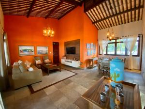 a living room with orange walls and a dining room at Casa Cantinho do Girassol in Natal