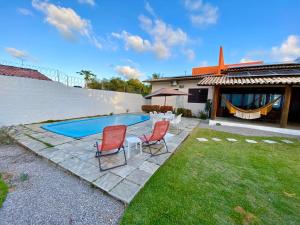 a backyard with a swimming pool and two chairs at Casa Cantinho do Girassol in Natal