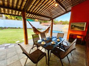 einen Tisch mit Stühlen und eine Hängematte auf der Terrasse in der Unterkunft Casa Cantinho do Girassol in Natal