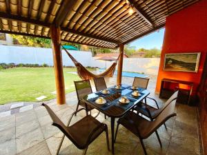 a table with chairs and a hammock on a patio at Casa Cantinho do Girassol in Natal