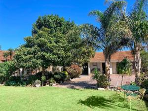 a house with palm trees in a yard at Albert Road Garden Guest House in Port Elizabeth