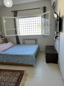 a small bedroom with a bed and a window at APPART SARAH Plage in Hammamet Nord