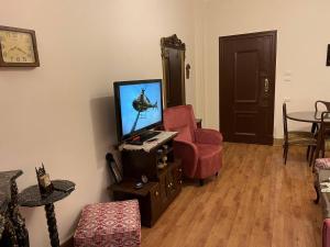 - un salon avec une télévision et une chaise rouge dans l'établissement Wonderful Apartment Place in Dokki, au Caire