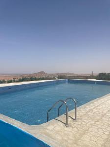 a large swimming pool with blue water and mountains in the background at Maison d'Hôte - Le Beau Panorama in Berkawe