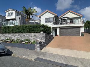 a house with a stone retaining wall and a driveway at Te Rukutai in Auckland