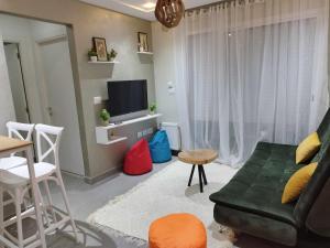 sala de estar con sofá verde y TV en Coquette Appartement, en Boumhel El Bassatine