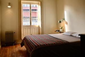 een slaapkamer met een bed en een groot raam bij Casa Astória - City Centre Historical Building with Amazing River View in Porto