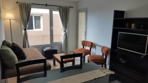 een woonkamer met een bank, stoelen en een televisie bij Cara Sur Bariloche in Bariloche +1 foto