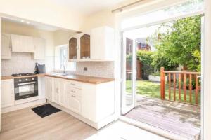 a kitchen with white cabinets and a sliding glass door at Beautiful Modern Home - Free Parking & Long Stays in Blackpool