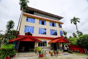 a building with blue windows and palm trees at Ekora Resort in Hatikhuli