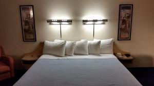 a bed with white pillows in a hotel room at Days Inn by Wyndham Buena Park in Buena Park