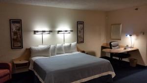 a hotel room with a large bed and a chair at Days Inn by Wyndham Buena Park in Buena Park