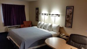 a hotel room with a large bed and a table at Days Inn by Wyndham Buena Park in Buena Park