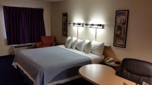 a hotel room with a bed and a chair and a table at Days Inn by Wyndham Buena Park in Buena Park
