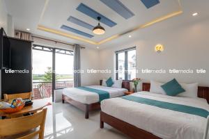 two beds in a room with a balcony at Rockmouse Centre River Villa Hoi An in Hoi An