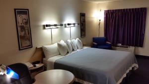 a hotel room with a large bed and a chair at Days Inn by Wyndham Buena Park in Buena Park