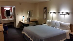 a hotel room with a large bed and a desk at Days Inn by Wyndham Buena Park in Buena Park