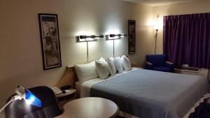 a hotel room with a bed and a chair at Days Inn by Wyndham Buena Park in Buena Park