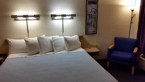 a hotel room with a bed and a blue chair at Days Inn by Wyndham Buena Park in Buena Park