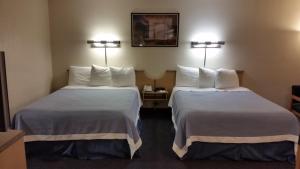 a hotel room with two beds and two lamps at Days Inn by Wyndham Buena Park in Buena Park