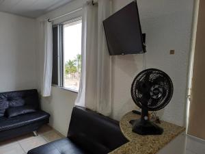 een woonkamer met een ventilator en een bank bij Aconchegante studio frente mar com vista CANTO DO FORTE in Praia Grande